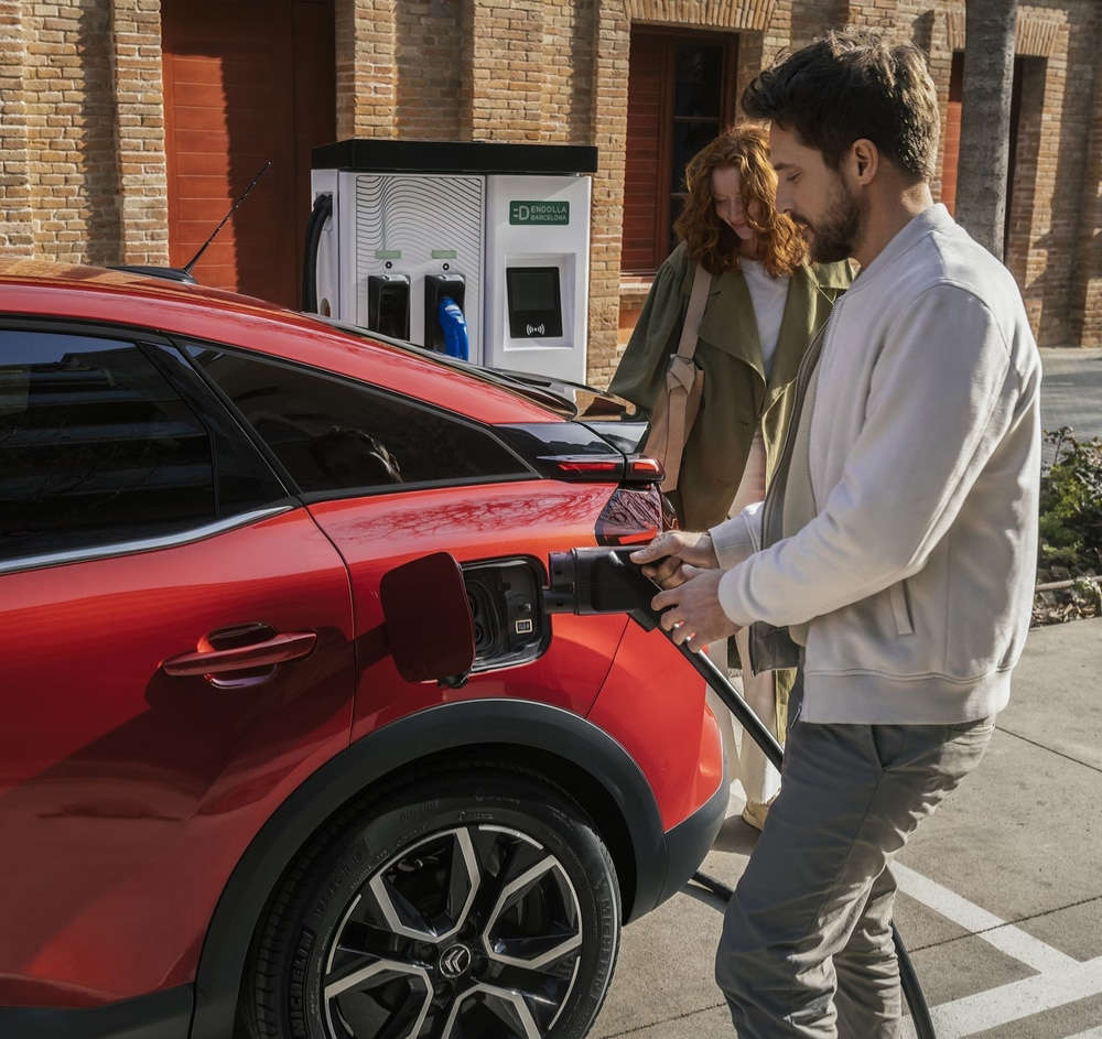 Чоловік вставляє вилку у зарядне гніздо електромобіля Citroën ë-C4