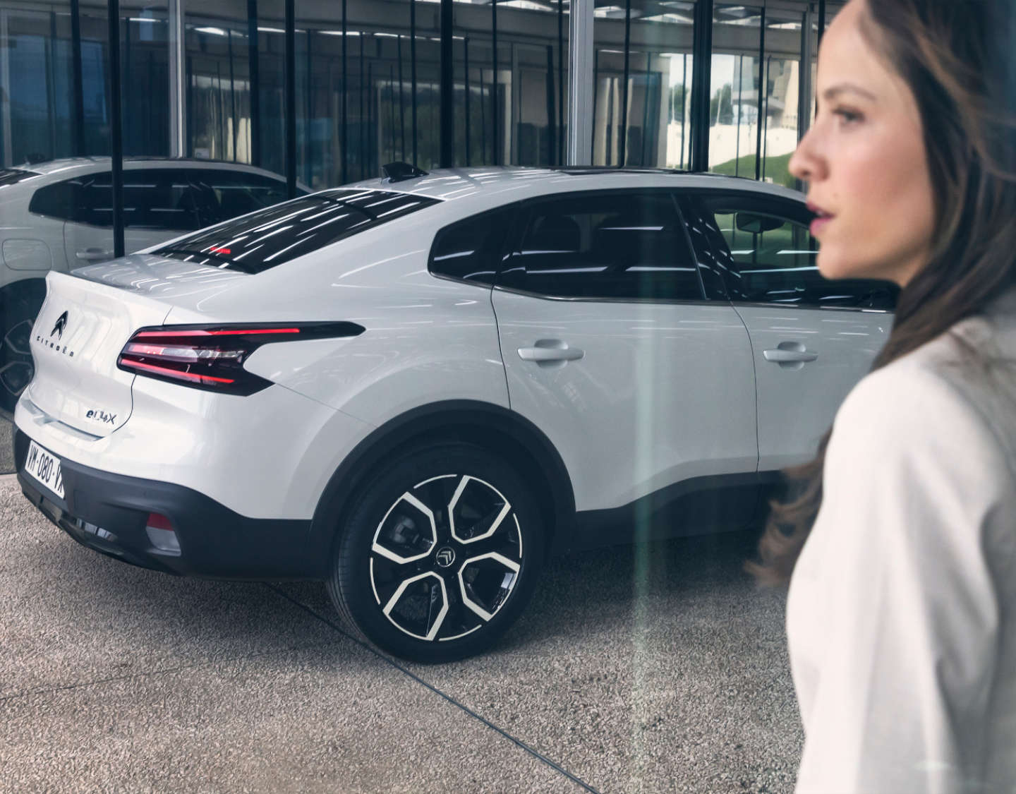 Молода жінка біля білого Citroën ë-C4 X