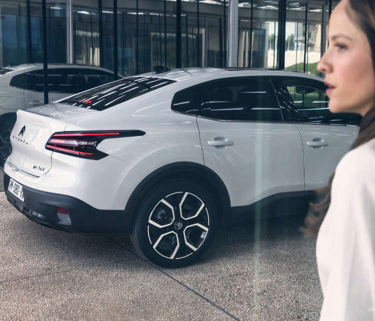 Молода жінка біля білого Citroën ë-C4 X